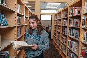 Student at the library holding a book 